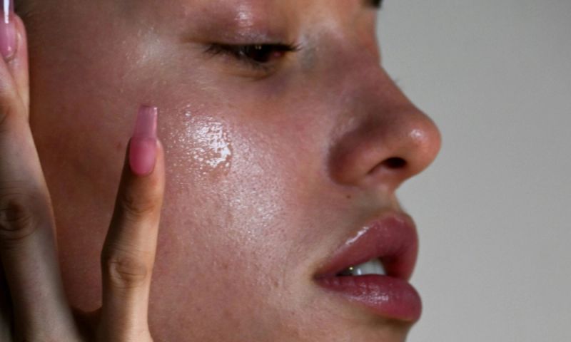 Close side view of woman applying a skin serum on cheek