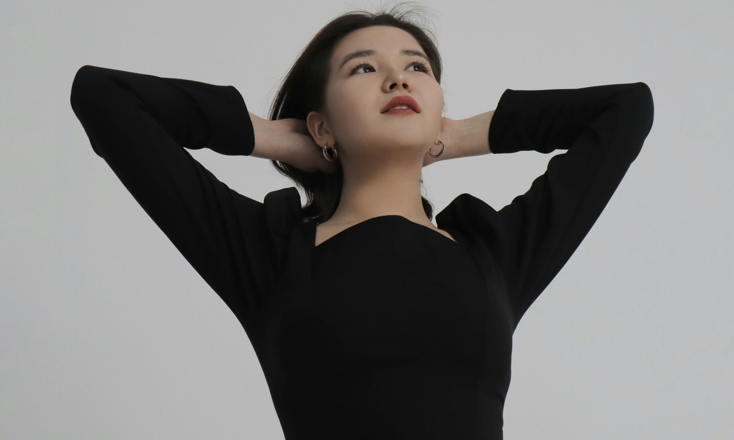 Asian woman with arms behind her head looking up