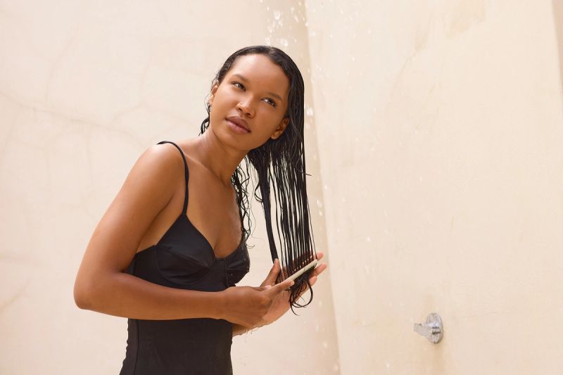 Long Hair Shower Relaxation: Woman Gently Combing Wet Hair Under Refreshing Water Stream. Calm, Reflective Mood, Emphasizing Self-Care, Tranquility, and Natural Beauty In Outdoor Setting. Ideal For Wellness And Beauty Themes.