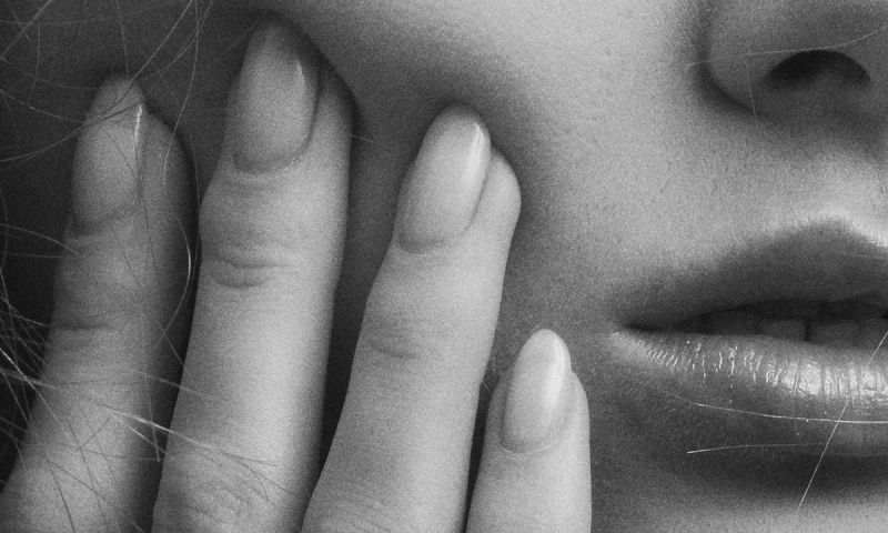 black and white close up of woman's hand on cheek