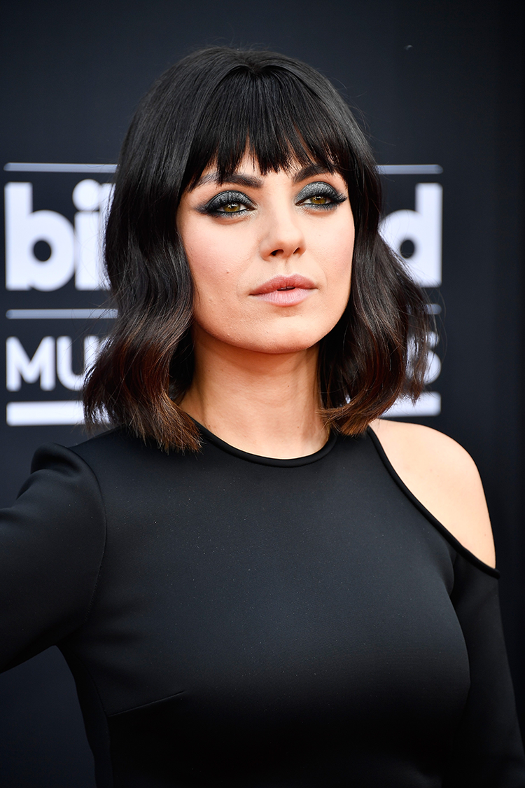 Mila Kunis with short black hair and bangs in black cut-out dress