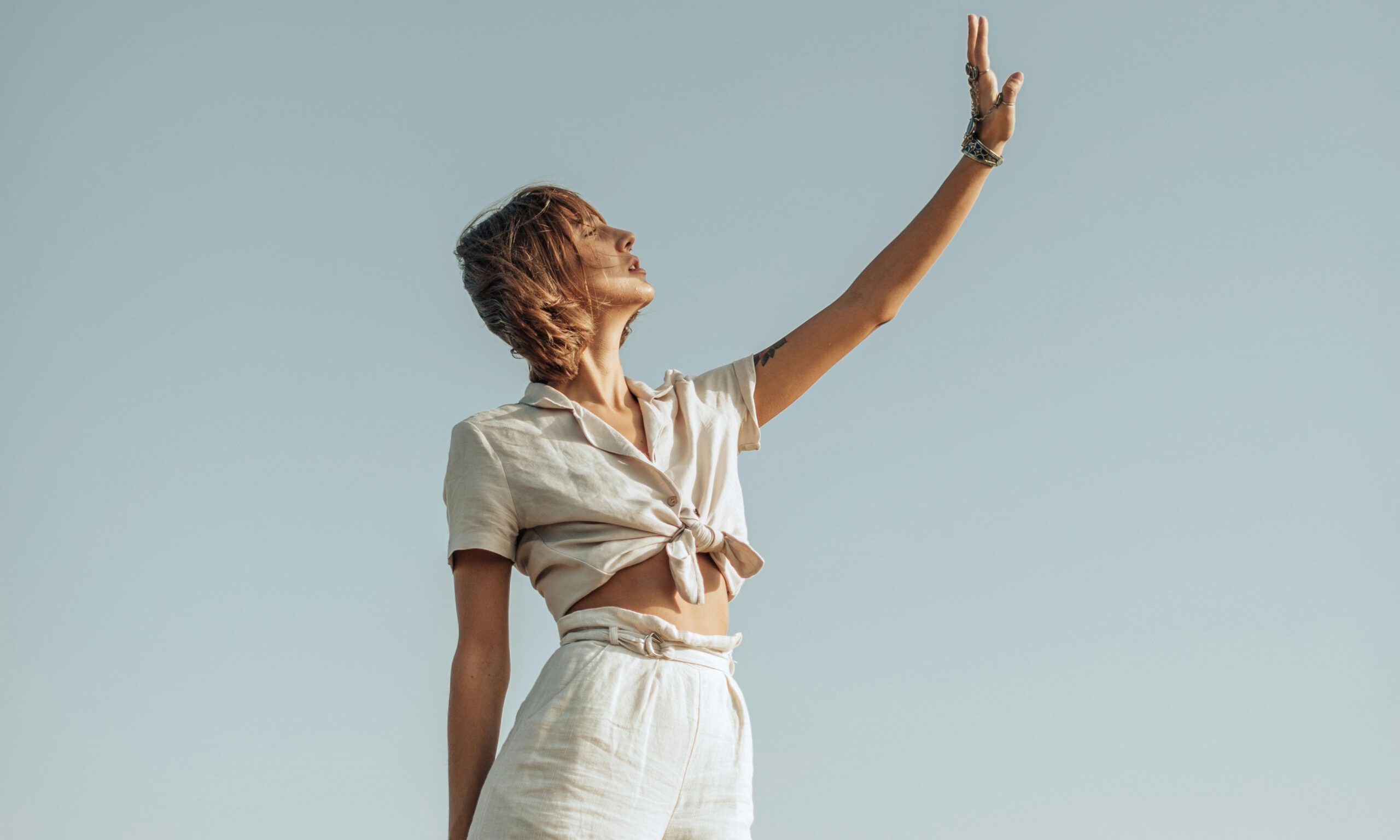woman outdoors holding her hand up to the sun