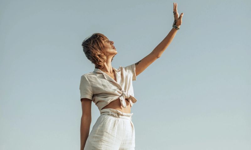 woman outdoors holding her hand up to the sun