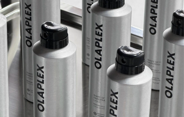 Several silver bottles of OLAPLEX Shape Set Hairspray arranged together in a black-and-white product shot.
