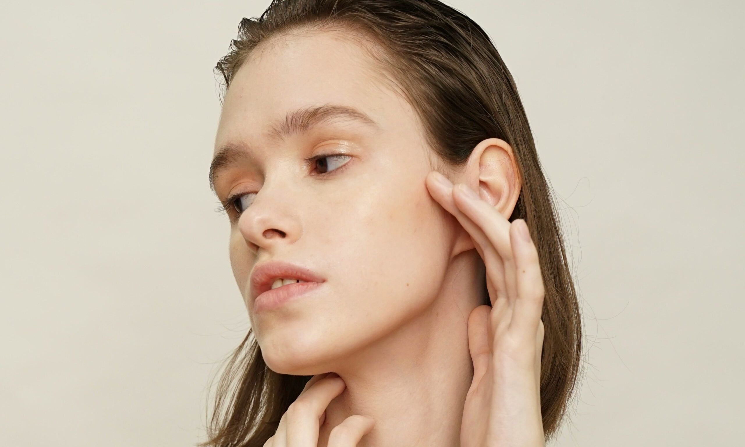 woman with bare skin toching face