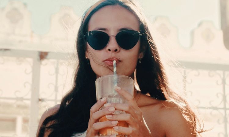 woman wearing sunglasses and drinking juice