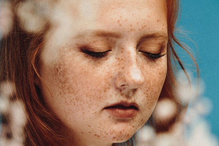 woman with eyes closed among flowers