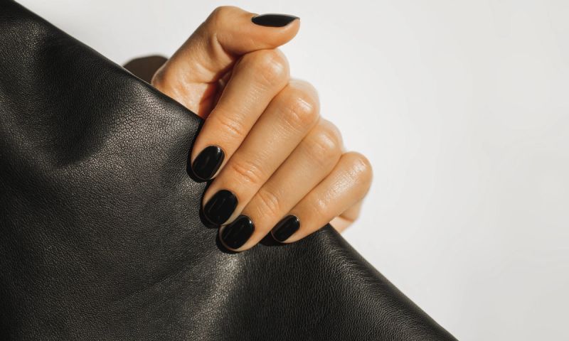 hand with black nails holding clutch
