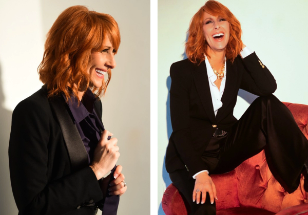 Wendy Braun poses in a black suit with soft waves, smiling in a studio setting with warm lighting