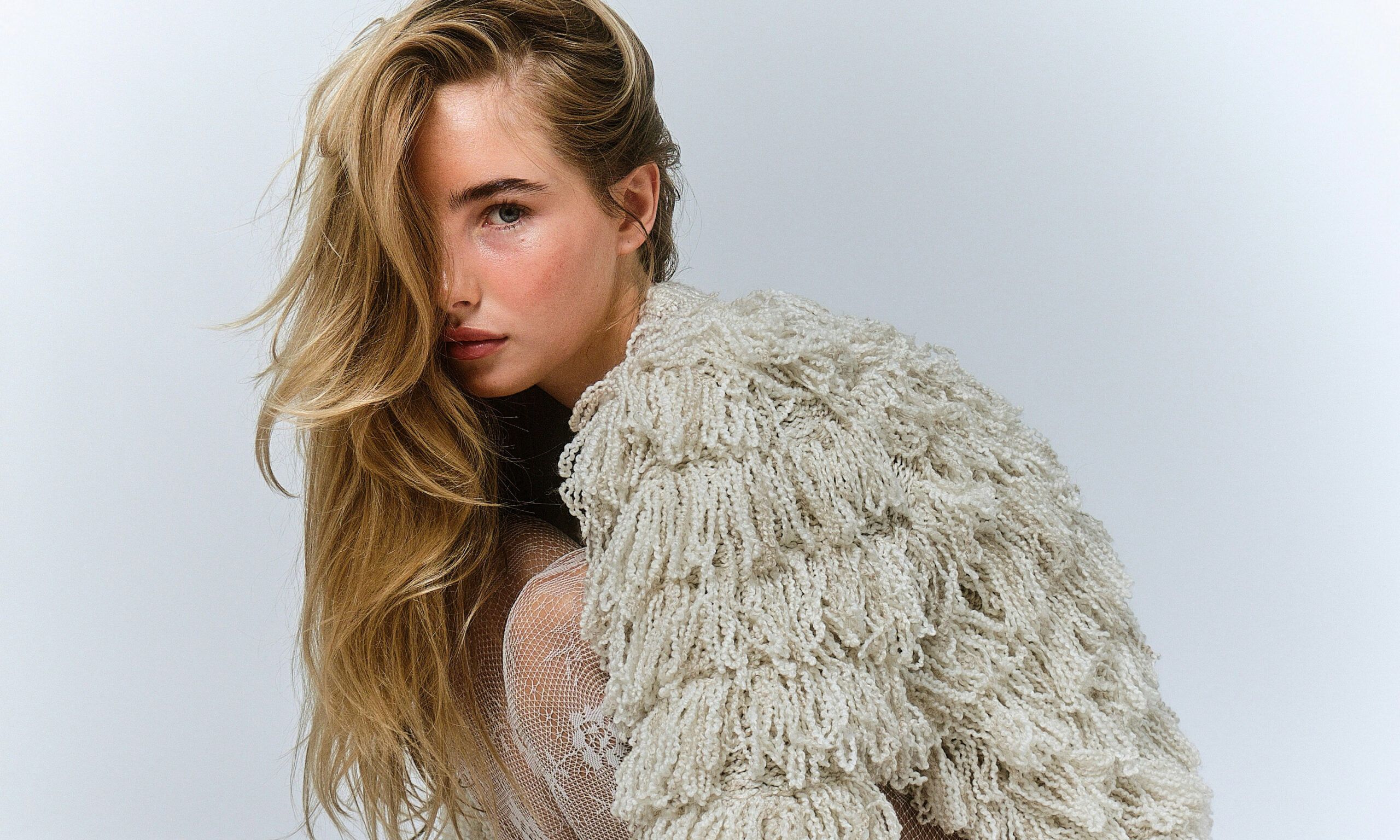 woman with blonde wavy hair wearing a shaggy coat