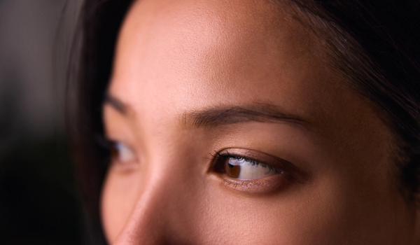 Close-up of a woman's smooth forehead, brow and brown eye as she glances to the side.