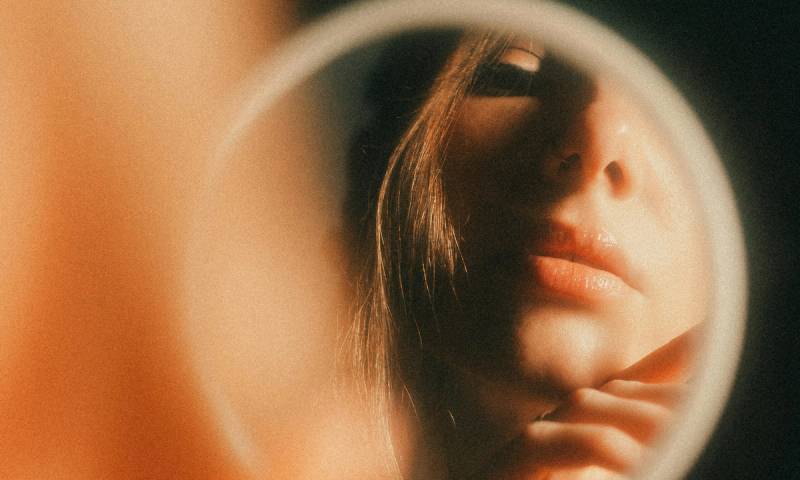 woman looking into magnifying mirror