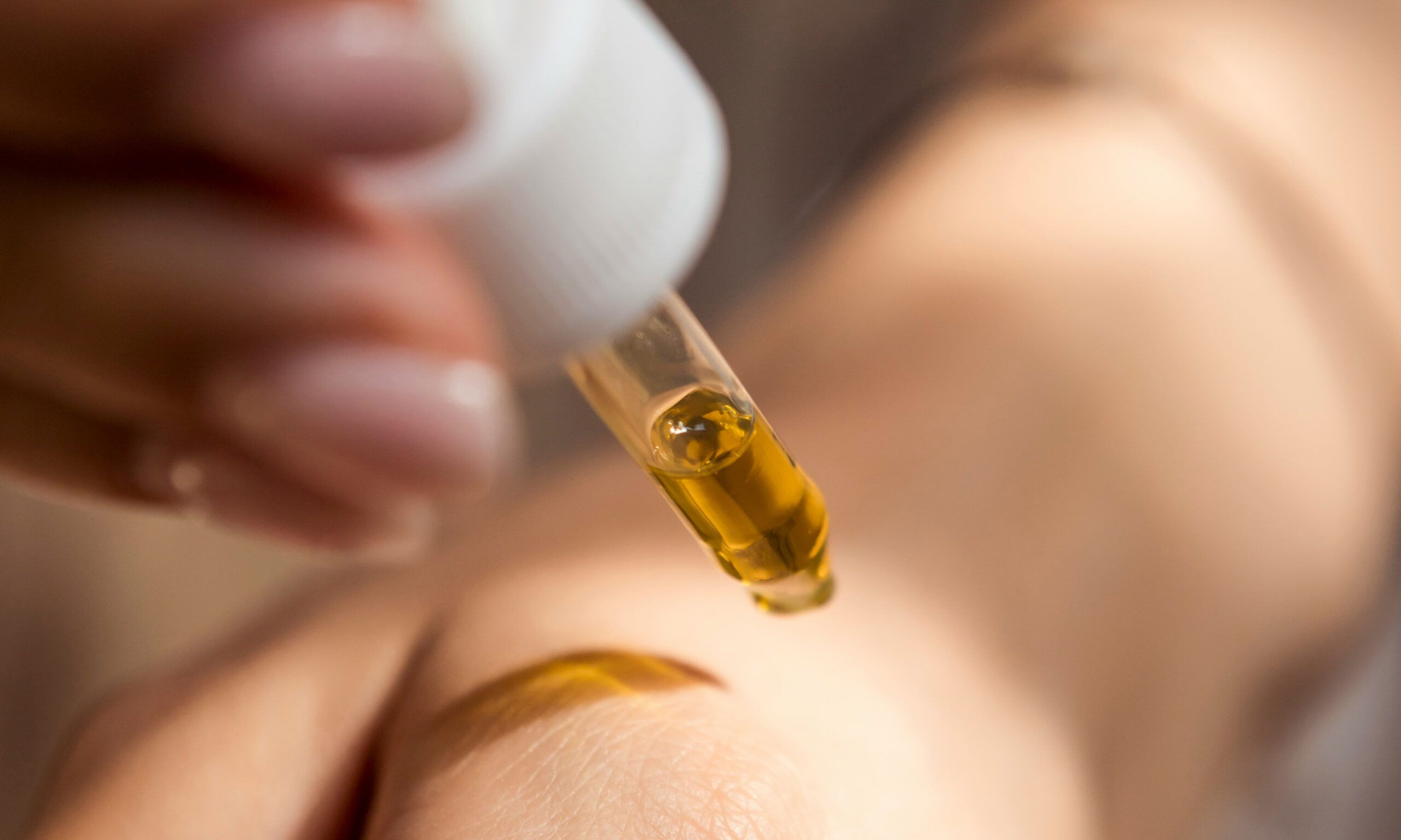 person putting dropper of serum on skin