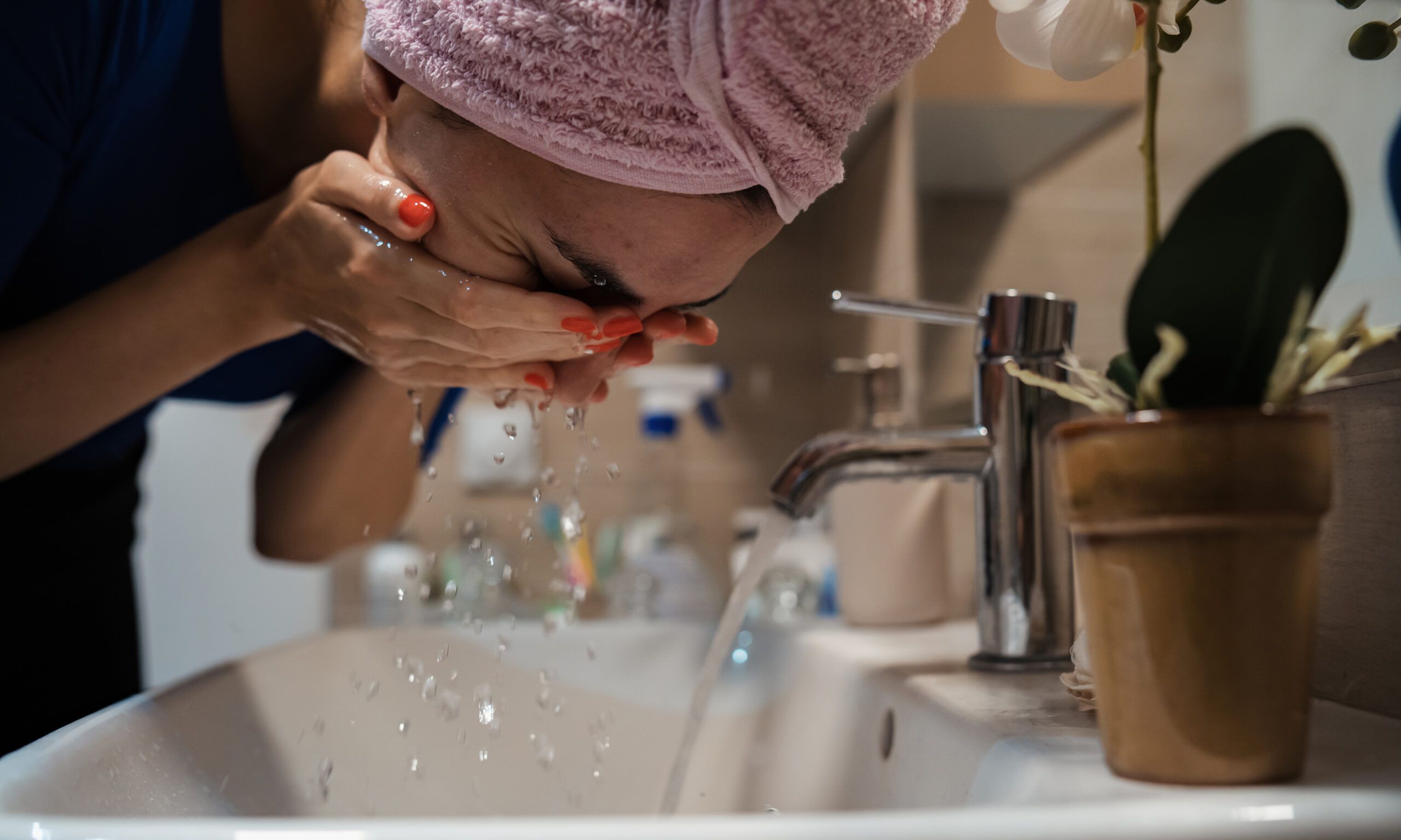woman rinsing face over sink