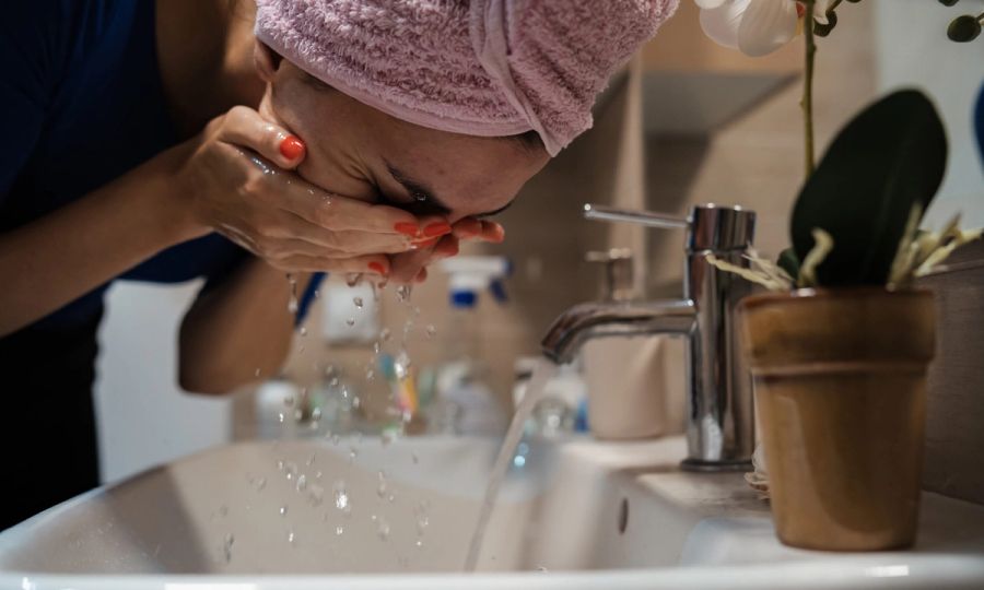 woman rinsing face over sink
