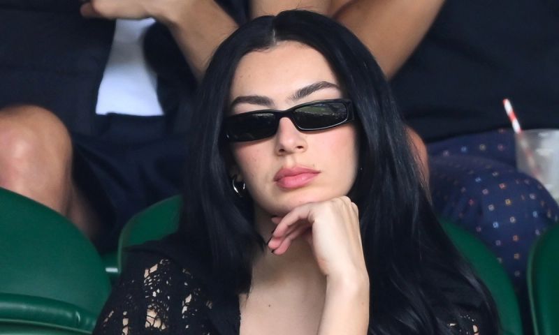 Charli XCX sitting in the Wimbledon stands wearing black sunglasses