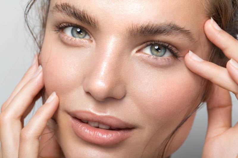 Close up studio shot of a beautiful woman with perfect skin, she touching her face