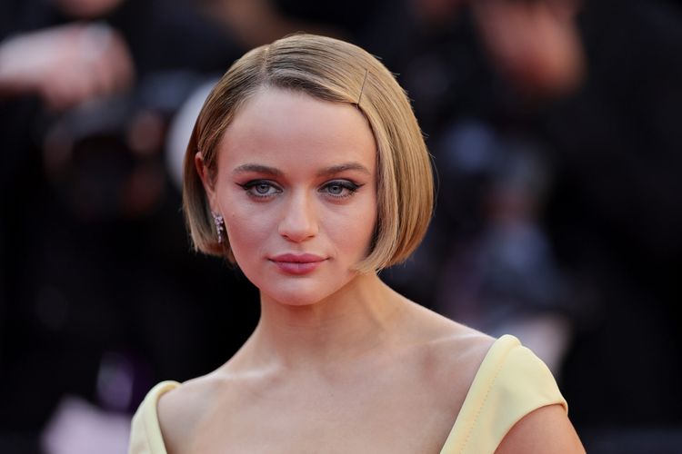 Joey King with a chin-length blonde bob posing on the red carpet in yellow dress