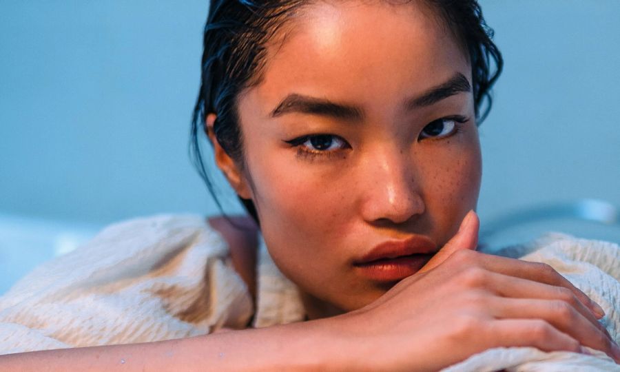 close up image of Asian woman's face sitting in front of blue background