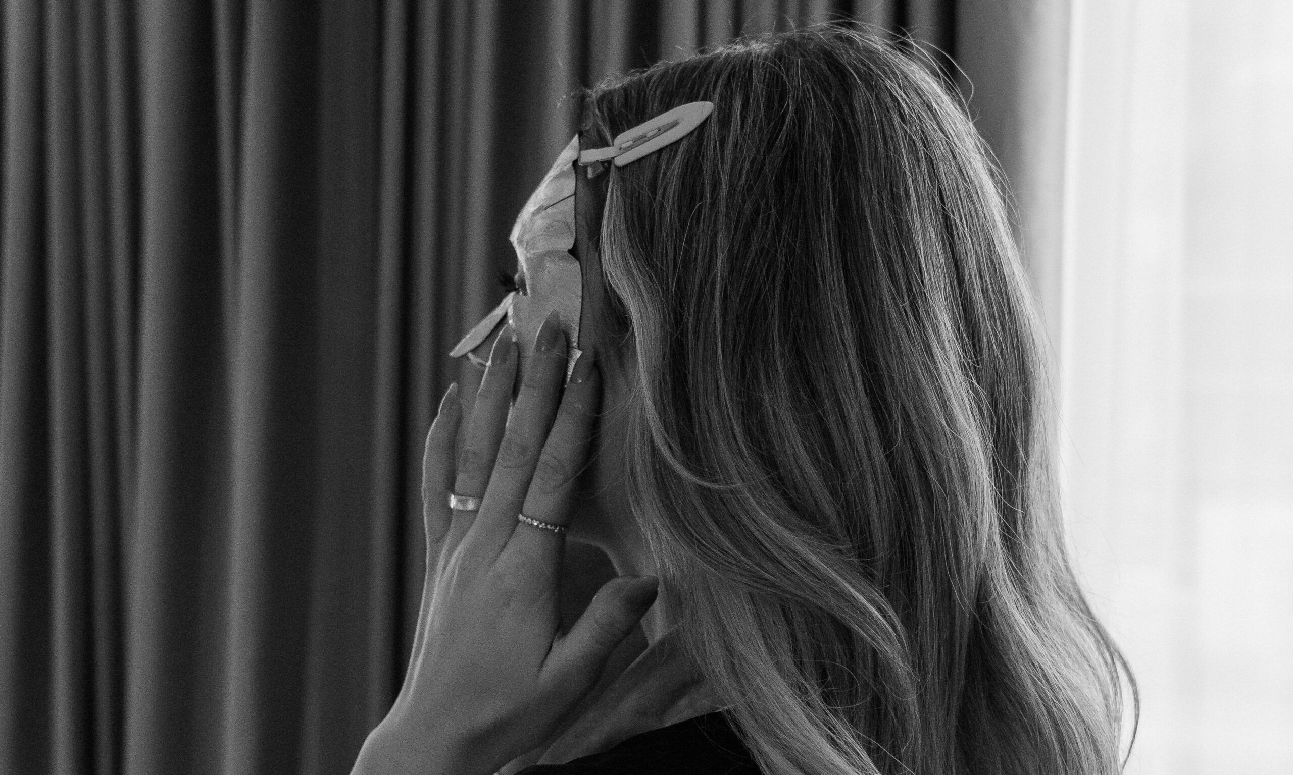 black and white image of woman putting on skin mask
