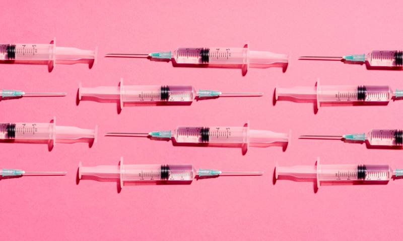 Syringe with injection or vaccine repetition pattern on pink background