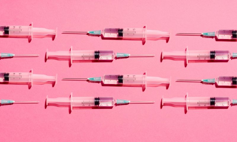 Syringe with injection or vaccine repetition pattern on pink background