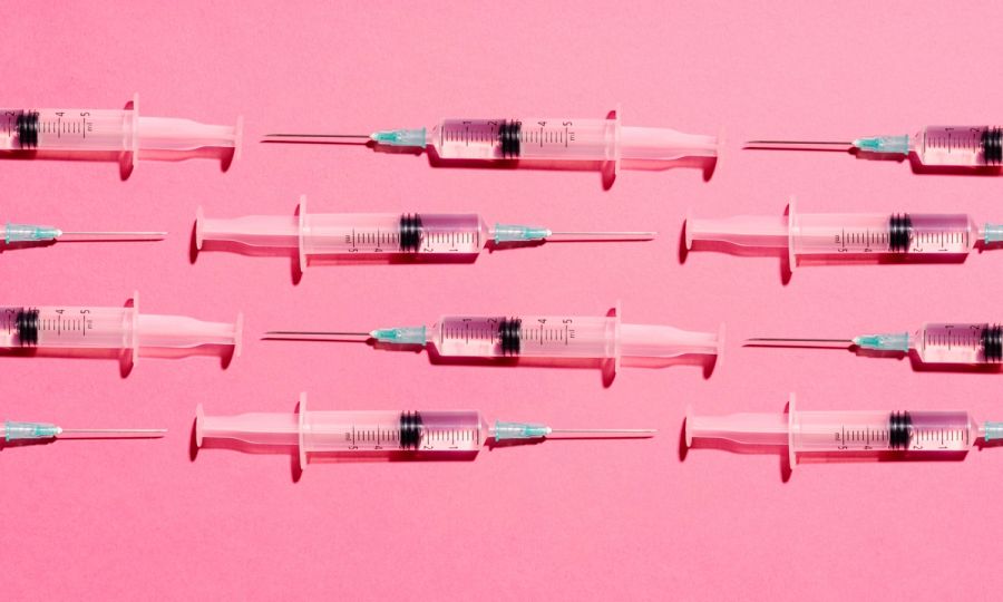 Syringe with injection or vaccine repetition pattern on pink background