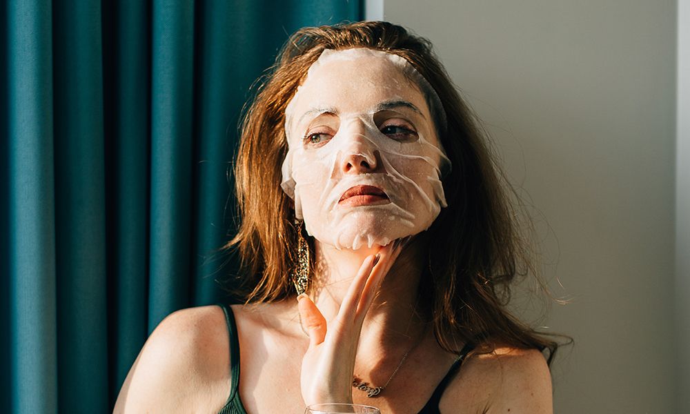 Young beautiful woman with a beaty mask and a glass of water at home