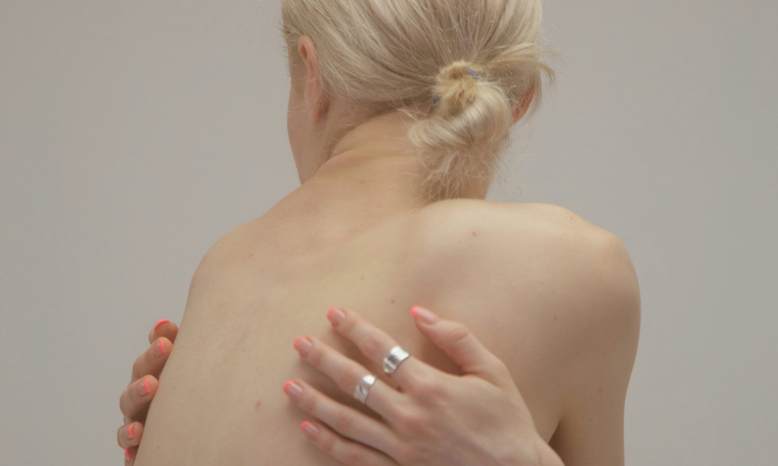 back view of blonde-haired woman with arms and hands crossed over her back