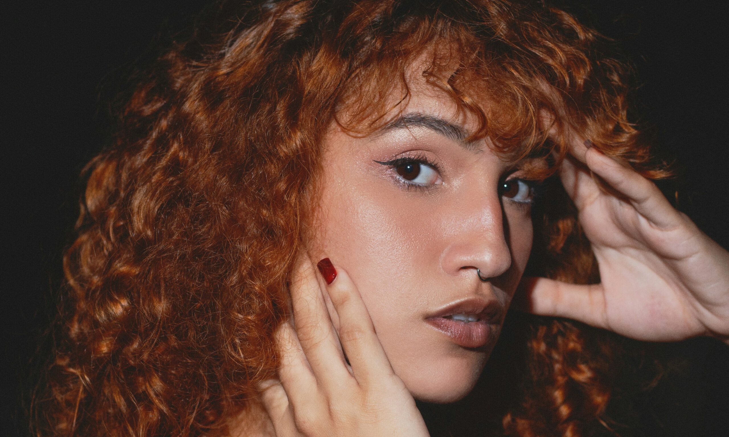 Photo of woman with curly red hair against black background