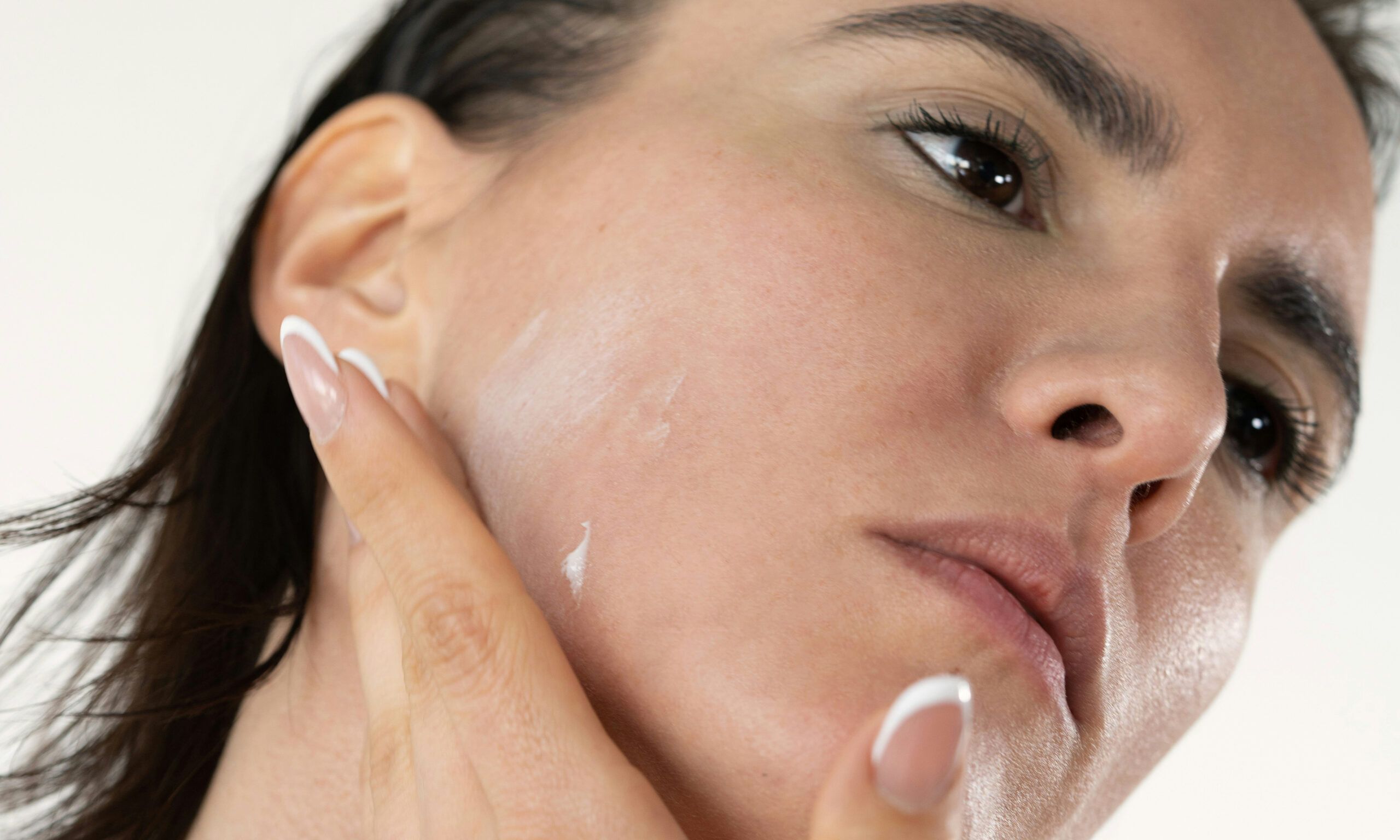 woman applying skin care cream on jawline