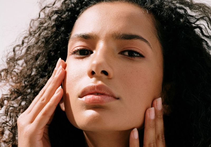 woman looking into camera and touching her face