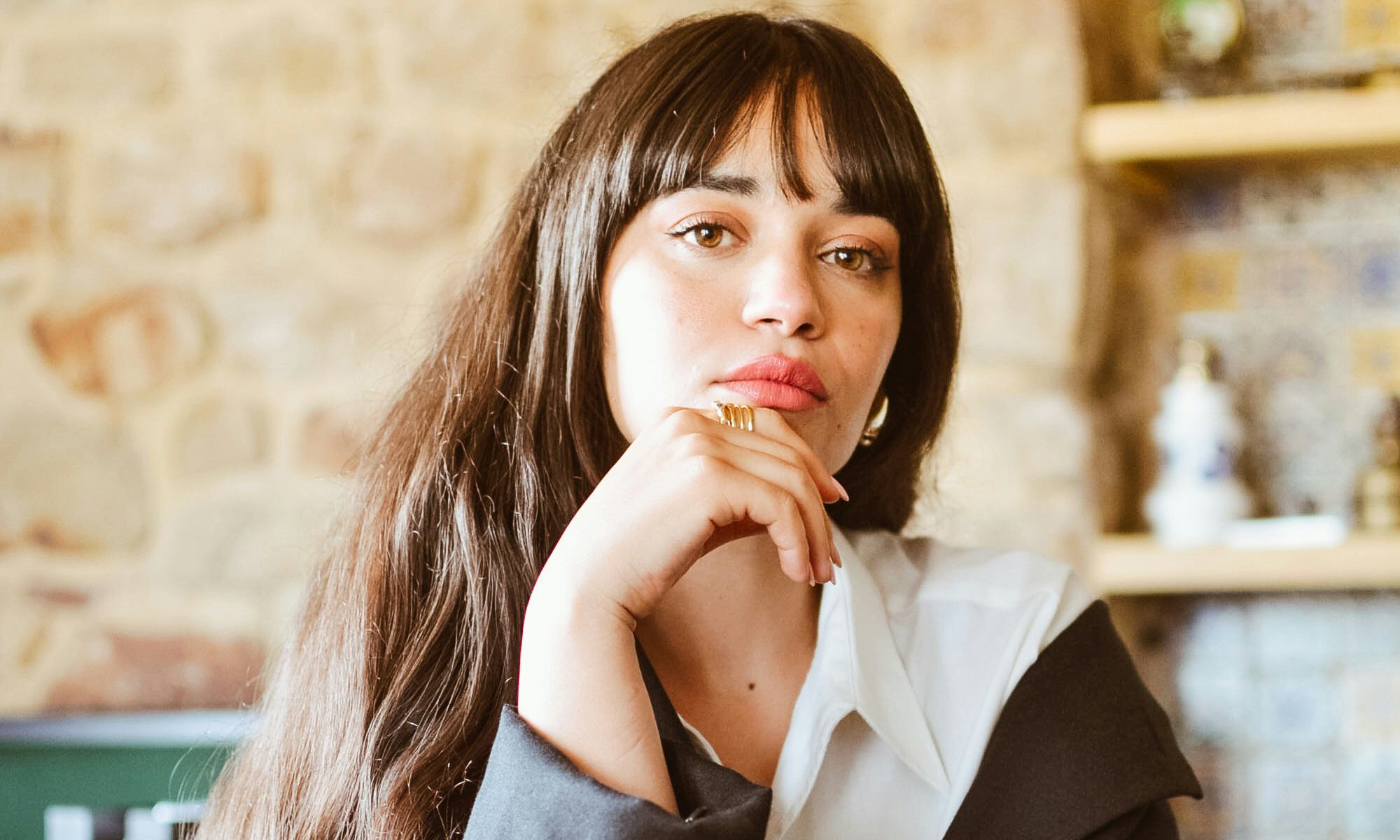 woman with bangs sitting with hand on her chin