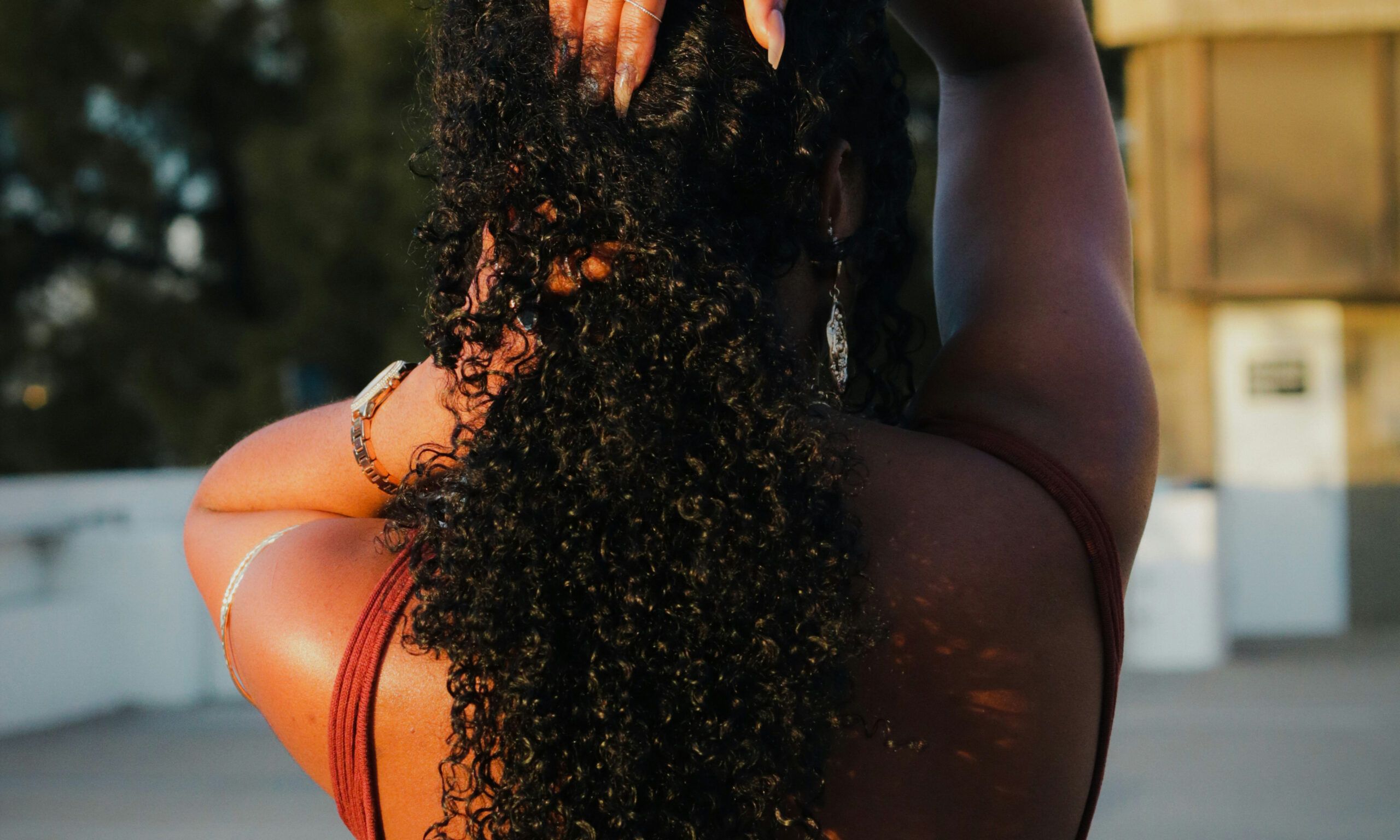 back view of woman touching curly natural hair