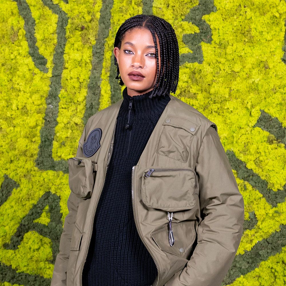 Willow Smith with a braided bob wearing a green jacket and black turtleneck 