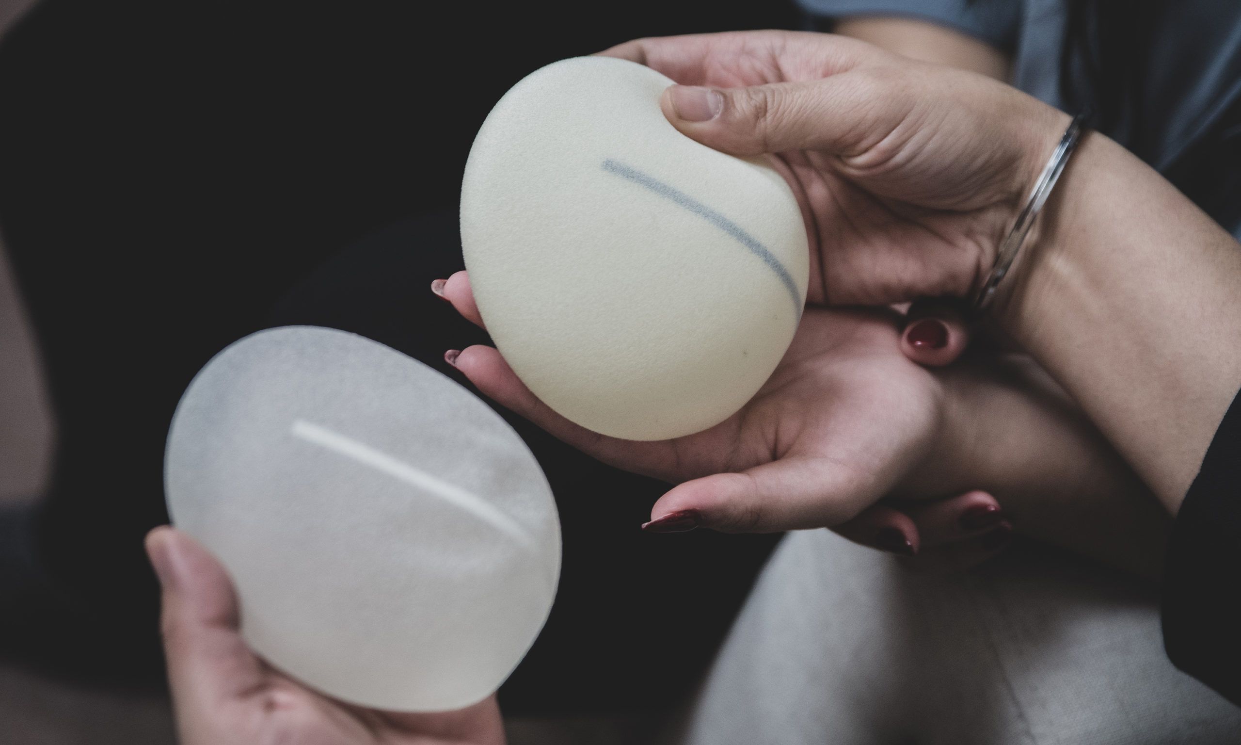 hands holding breast implants