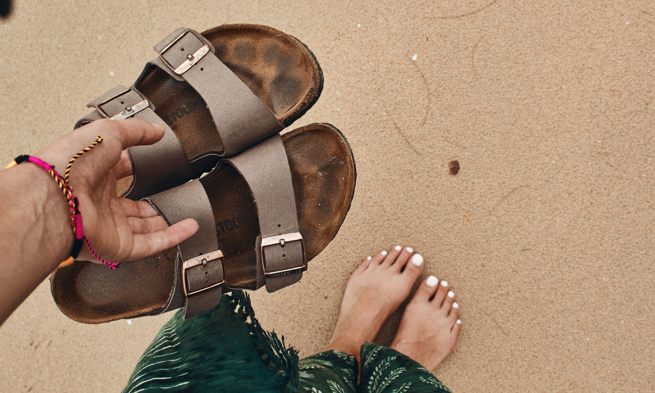 person holding pair of brown-and-black open toe sandals