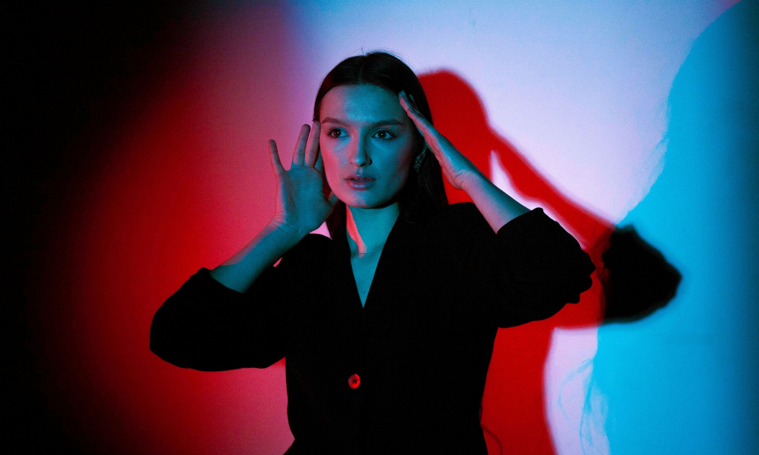 woman touching face in red and blue shadows