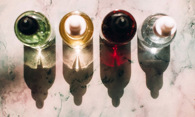 Top view of glass bottles with various moisturizing products placed in line on marble background