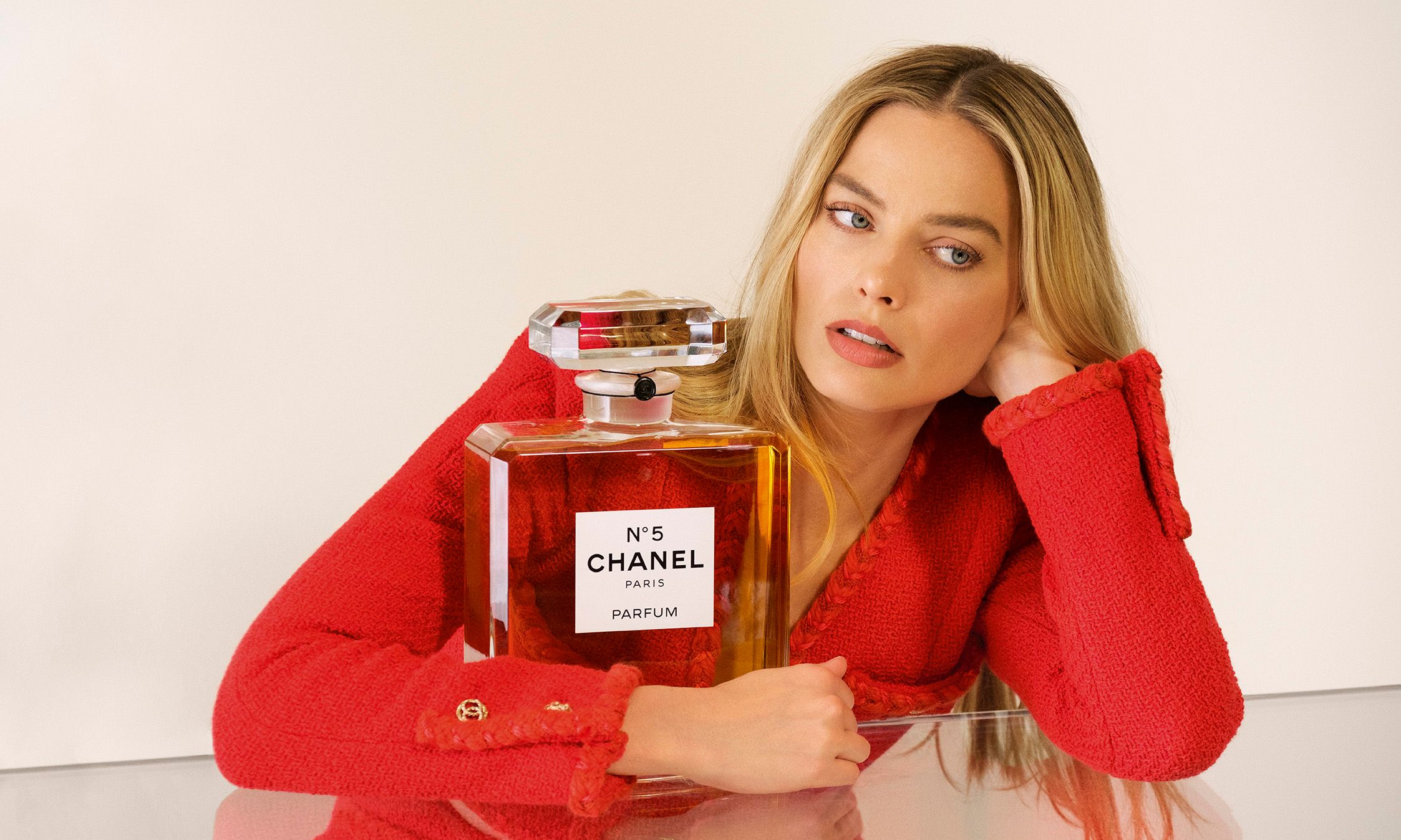 Margot Robbie holding large prop of Chanel no 5