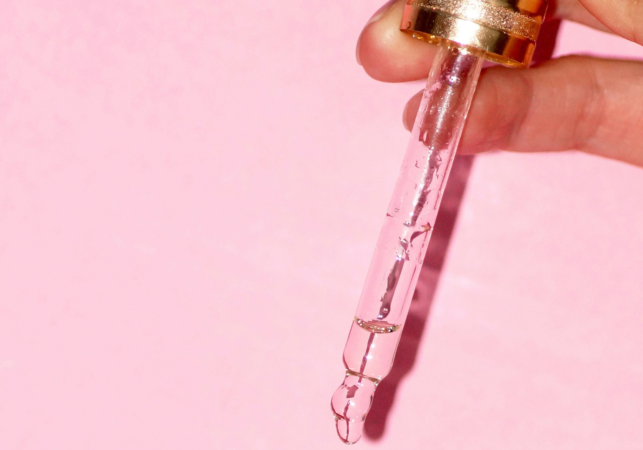 skin care dropper on pink background