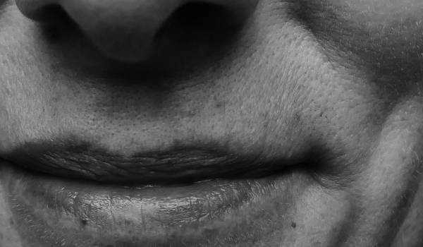Black-and-white close-up of mature lips with fine lines and visible skin texture.