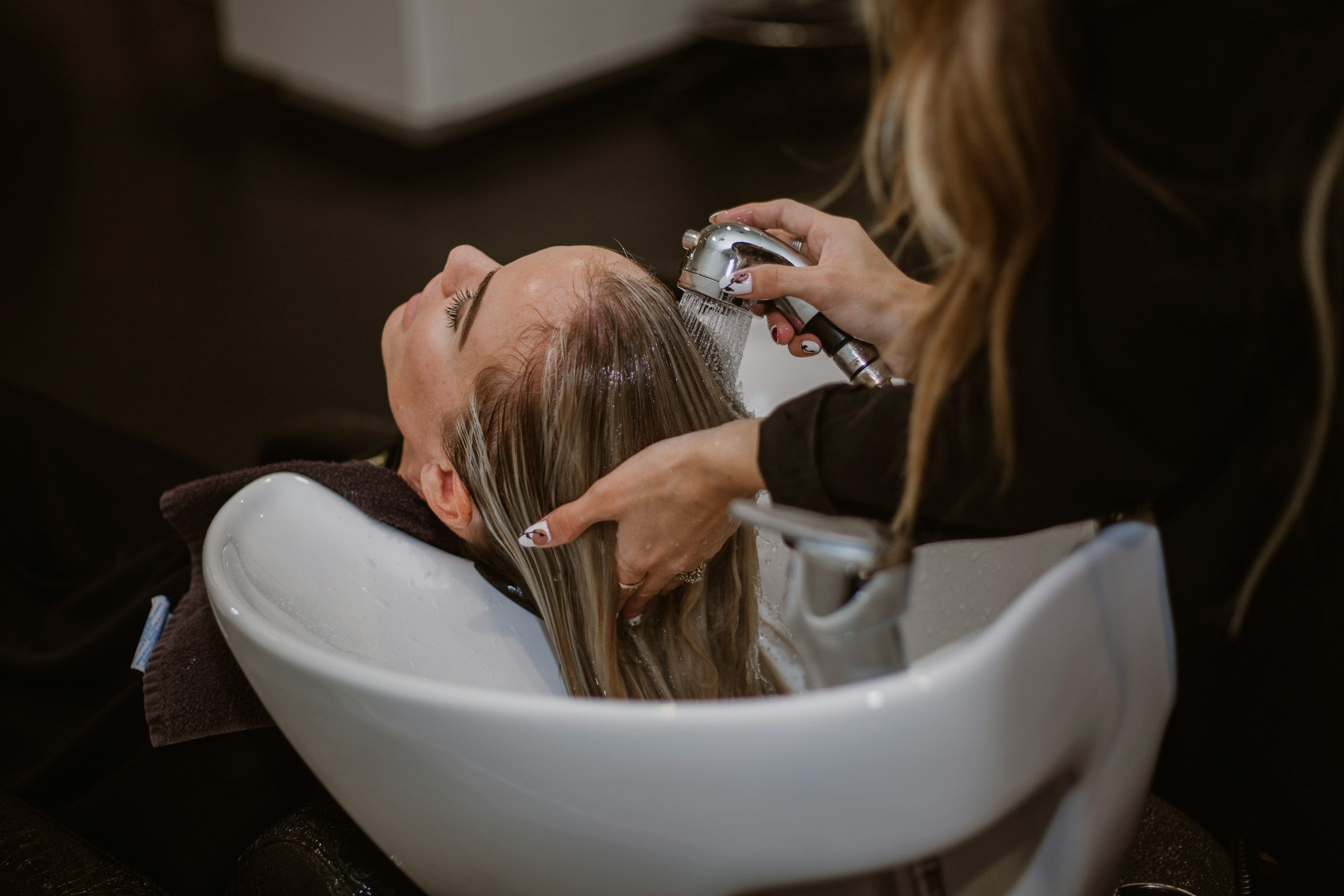 A woman getting her hair washed by a hairstylist