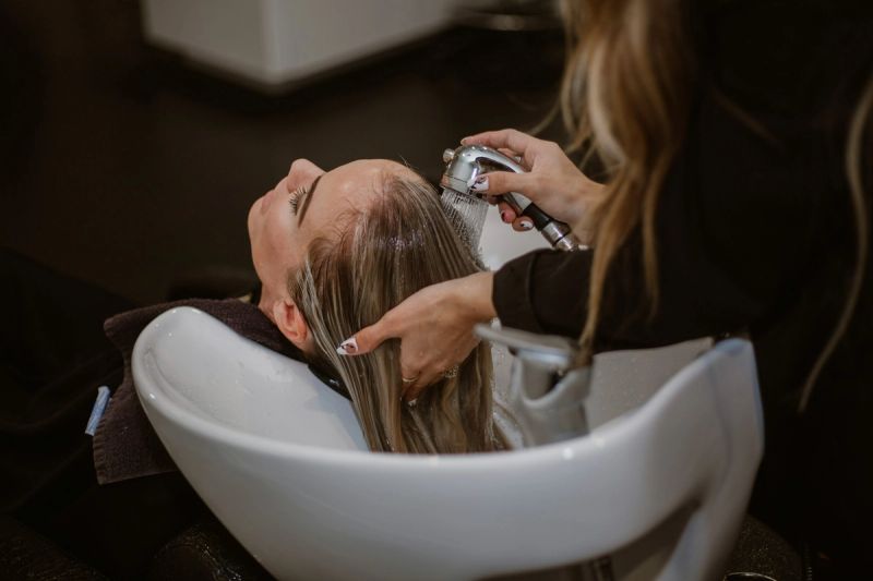 A woman getting her hair washed by a hairstylist