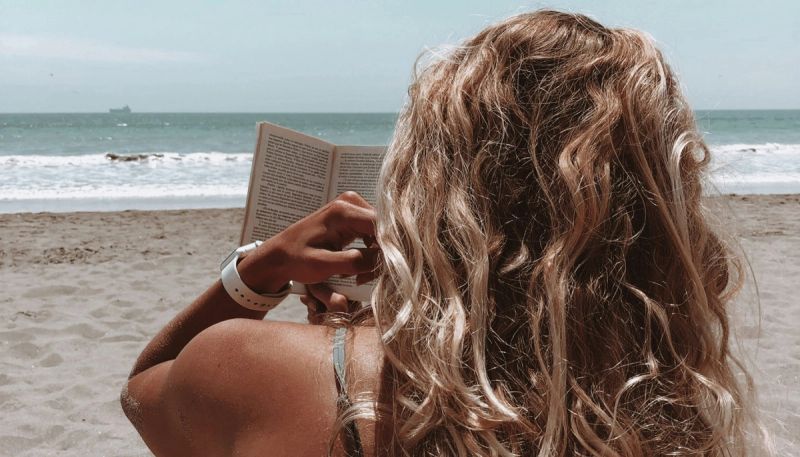 girl reading a book on the beach