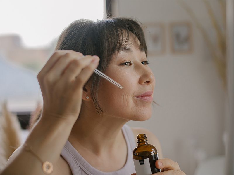 woman applying serum to face
