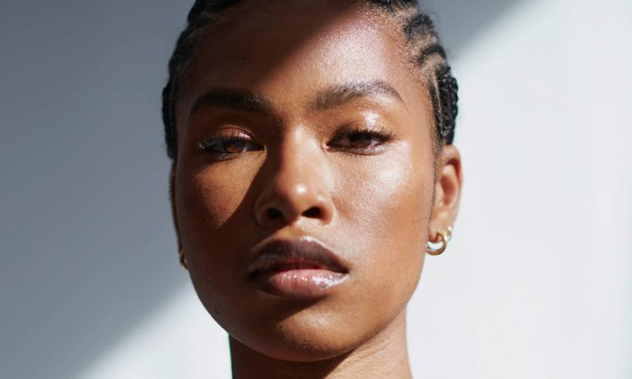 Front view of a black woman embracing her natural self in a portrait shot against a white background.