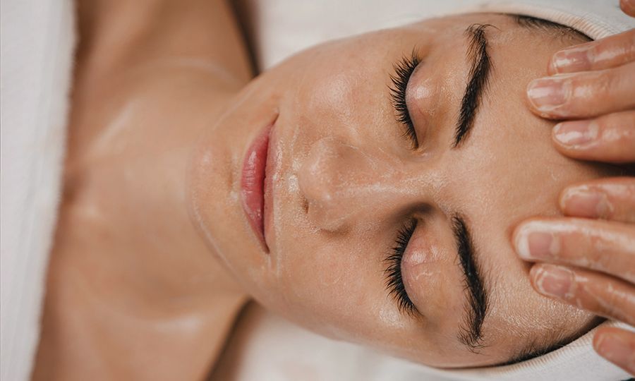 Shot of a beautiful young woman enjoying face massage at the beauty salon. Facial massage beauty treatment. Pinch and roll technique.