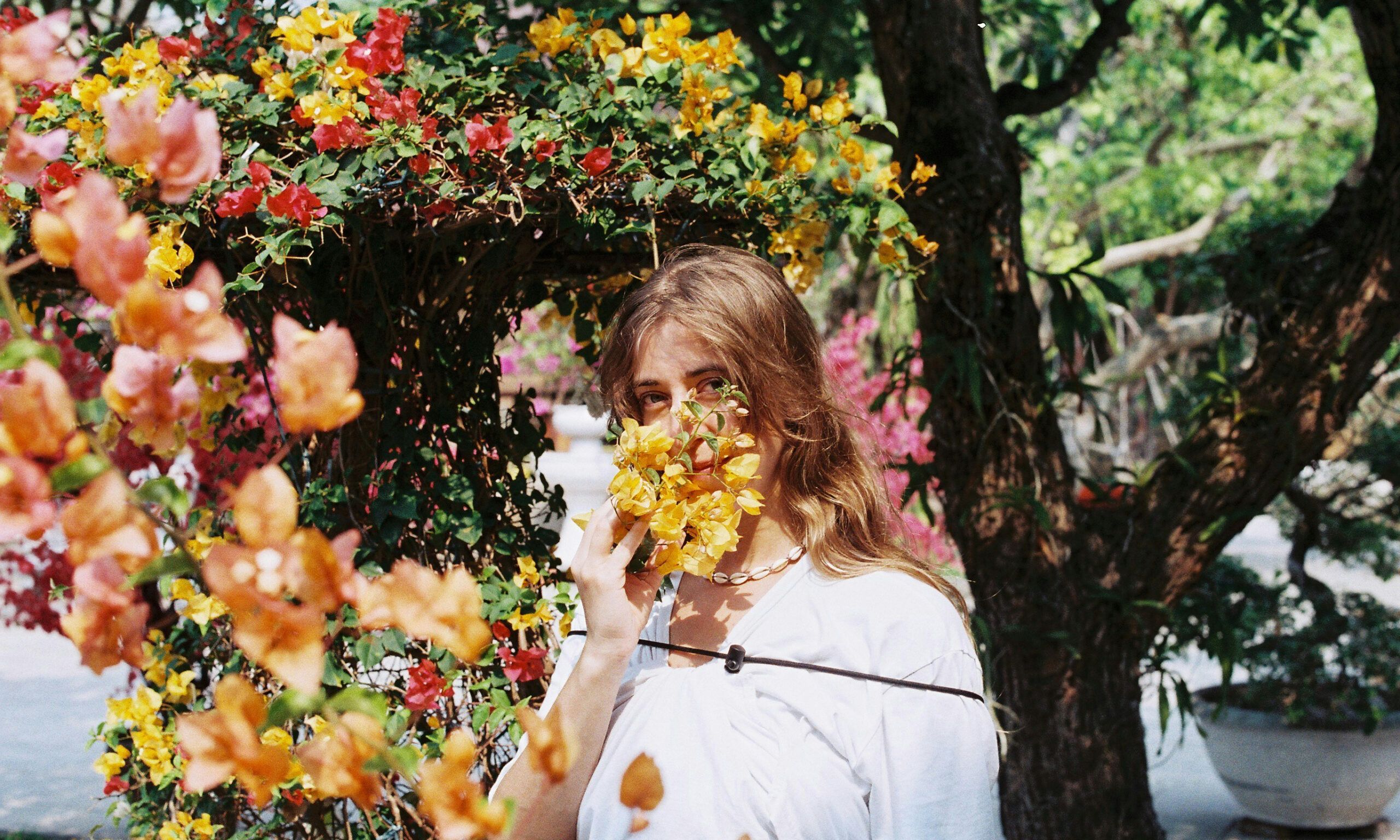 woman standing behind flowers on sunny day