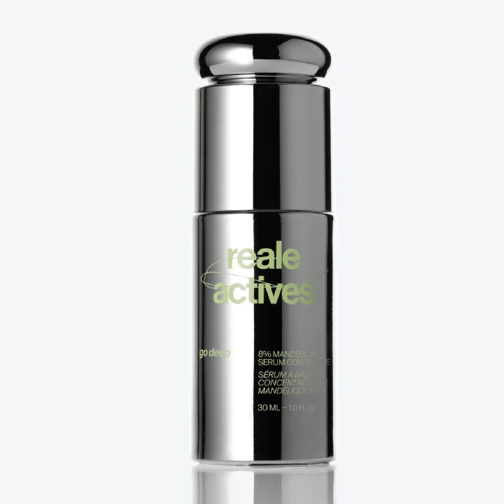 Reale Actives mandelic acid serum in a reflective chrome bottle with a rounded pump, featuring pale green branding and mirrored on a glossy surface against a white background.
